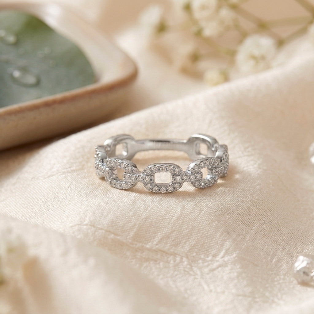 Photographie de produit d'une bague à maillons gourmette argentés entièrement pavée de cristaux, fond neutre.