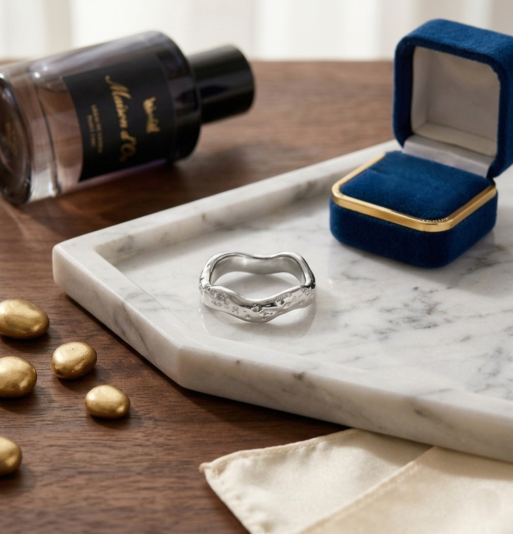Bijou bague Zoé argentée posée sur un plateau en marbre à côté d'un écrin en velours bleu roi.