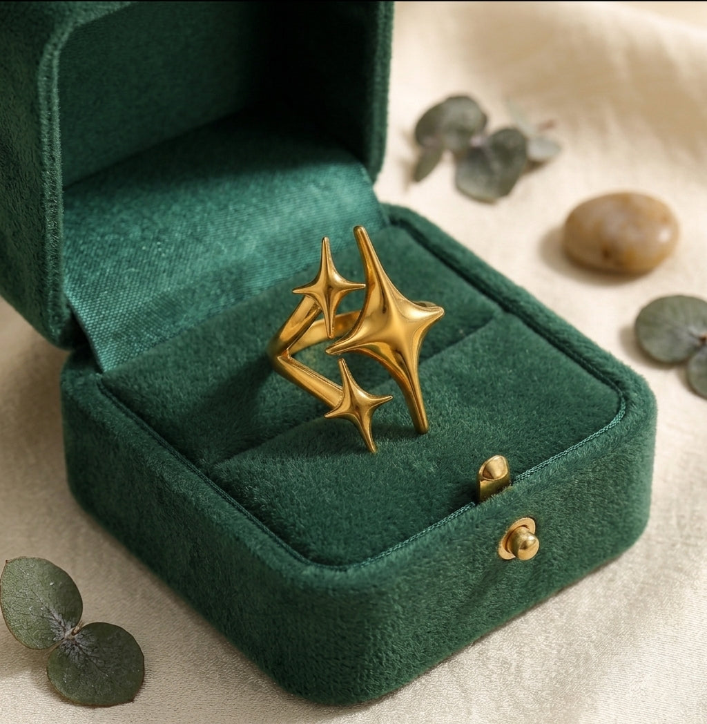 Bague triple étoile dorée Cassiopée Filante dans son écrin de velours vert bouteille ouvert.