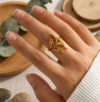 Bague Cassiopée Filante Or Solaire portée au doigt par une mannequin, pull en maille blanc.