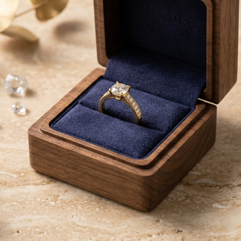Gros plan de la bague Sofia dorée et son grand cristal scintillant, présentée dans un écrin en bois de noyer haut de gamme.