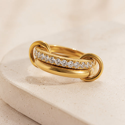 Bague Entrelacée Harmonie en acier inoxydable doré avec pierres blanches sur fond beige