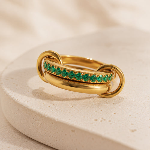 Bague Entrelacée Harmonie en acier inoxydable doré avec pierres vertes sur fond beige