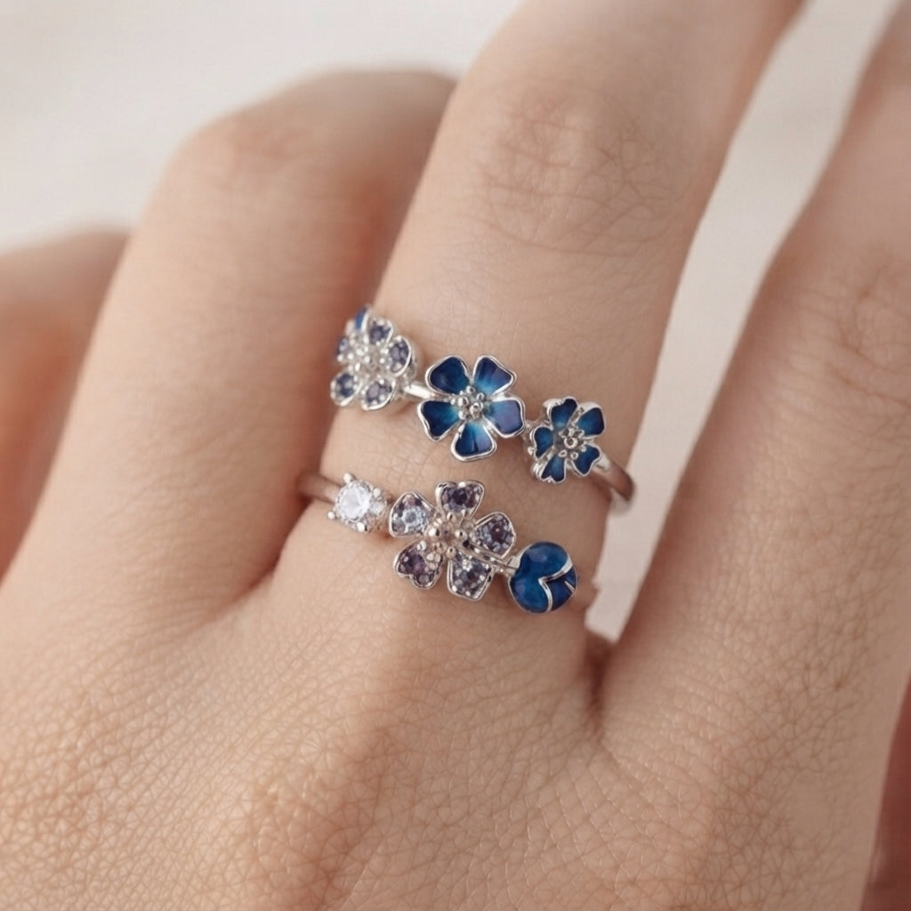Gros plan sur une bague fleur de pêcher argentée portée, avec ses pétales bleus délicats.