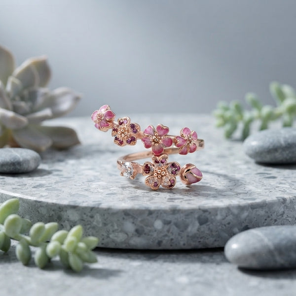 Bague fleur de pêcher dorée posée sur une pierre décorative, style élégant et minimaliste.