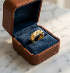 Bague Gabrielle Indomptable doré brut présentée dans son coffret en cuir marron et velours bleu, avec logo.