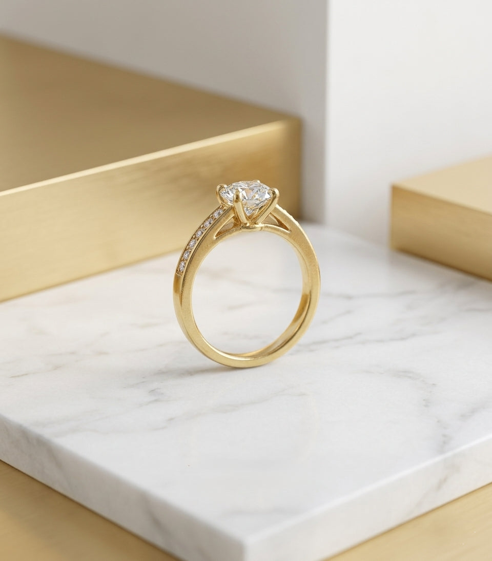 Bijou de créateur bague Sofia dorée posée sur un bloc de marbre blanc dans un décor minimaliste et sophistiqué.