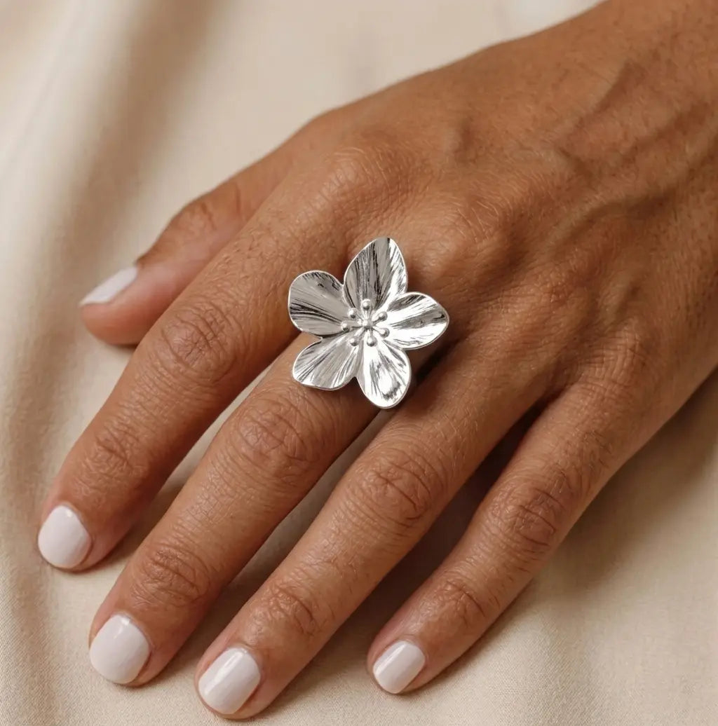 Gros plan d'une main de femme portant la bague Pétale argentée, mettant en avant son design floral et ses détails ciselés