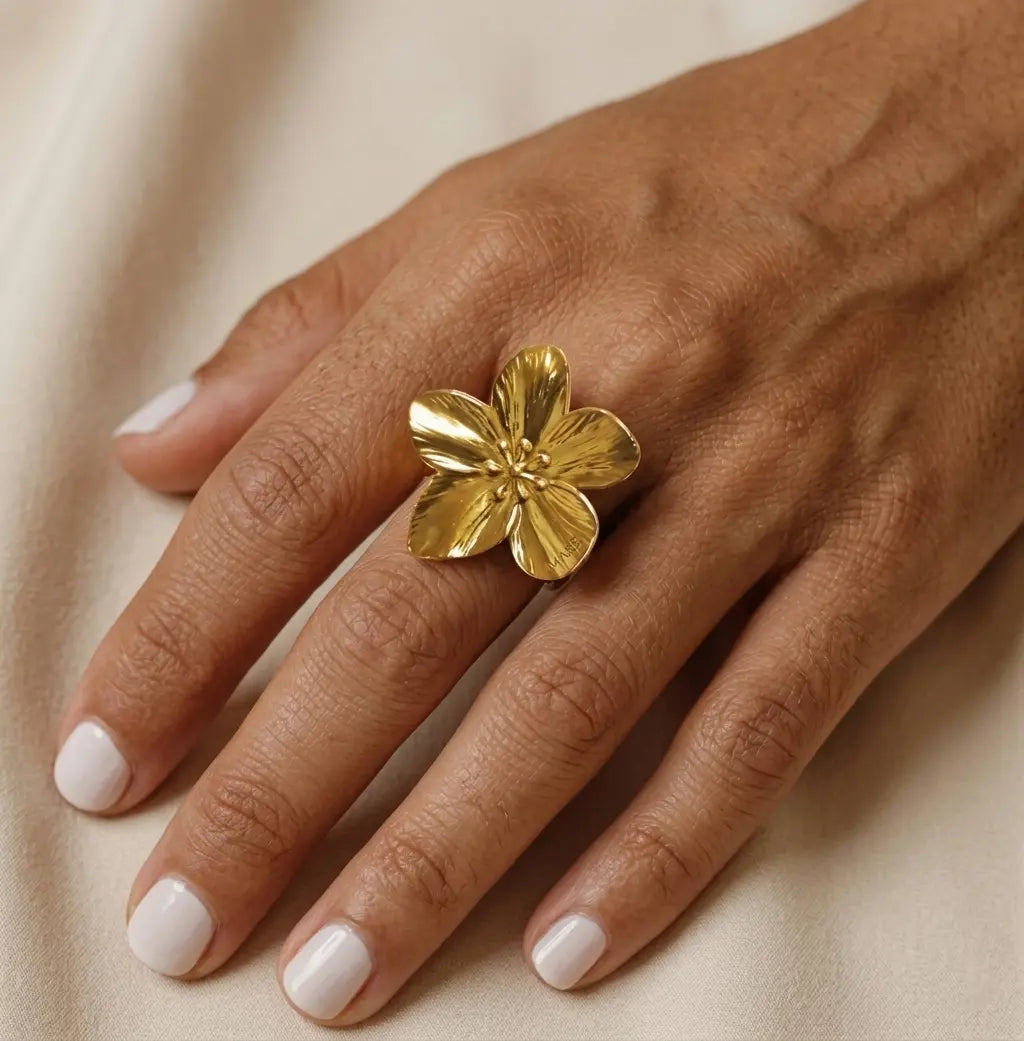 Gros plan d'une main de femme portant la bague Pétale dorée, mettant en avant son design floral et ses détails ciselés.