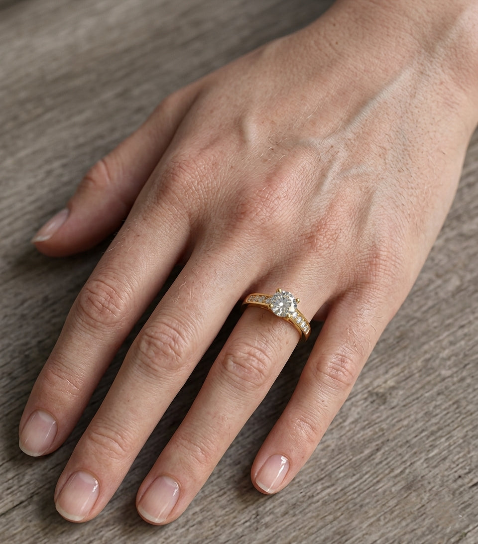 Bague solitaire pour femme en acier inoxydable doré, modèle Sofia - Éternelle, portée au doigt avec une manucure naturelle et élégante.