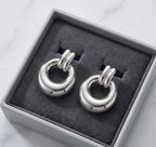 Paire de boucles d'oreilles argentées Alba présentée dans un écrin de luxe minimaliste gris avec un intérieur en velours anthracite, posé sur du marbre.