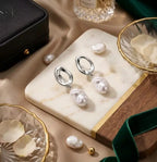 Mise en scène luxueuse des boucles d'oreilles Clarisse - Nacrée argent sur un plateau de marbre. Le métal précieux et la nacre de la perle d'eau douce créent un contraste moderne.