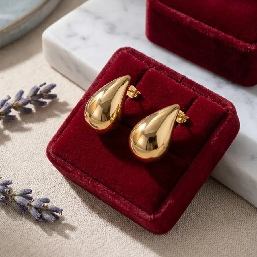 Boucles d'oreilles Inès Irrésistible dorées présentées dans un luxueux écrin en velours rouge profond. Mise en scène élégante pour une idée cadeau de haute joaillerie.