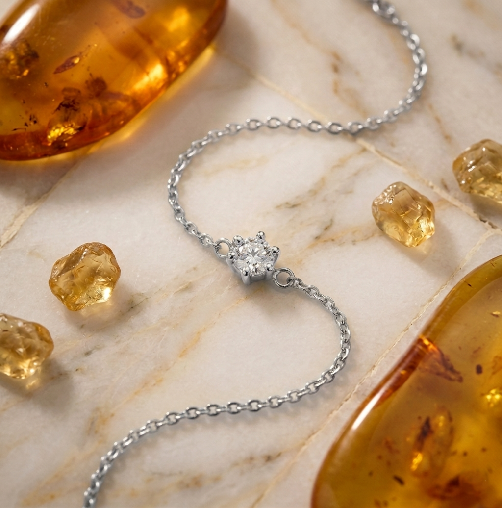 Bracelet Isaline Scintillante argenté posé sur du marbre, entouré de pierres d'ambre et citrine.