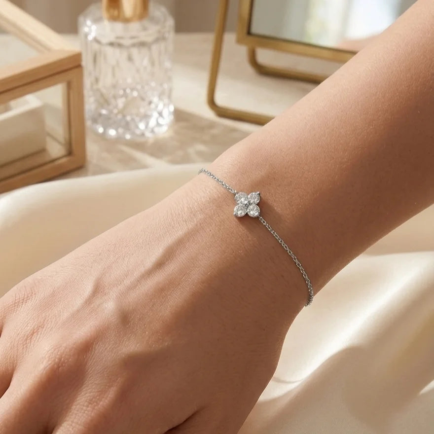 Bracelet Sia - Cristalline en finition argent porté au poignet. La fine chaîne dorée et le trèfle scintillant contrastent élégamment sur la peau, avec un arrière-plan flou suggérant un intérieur raffiné.