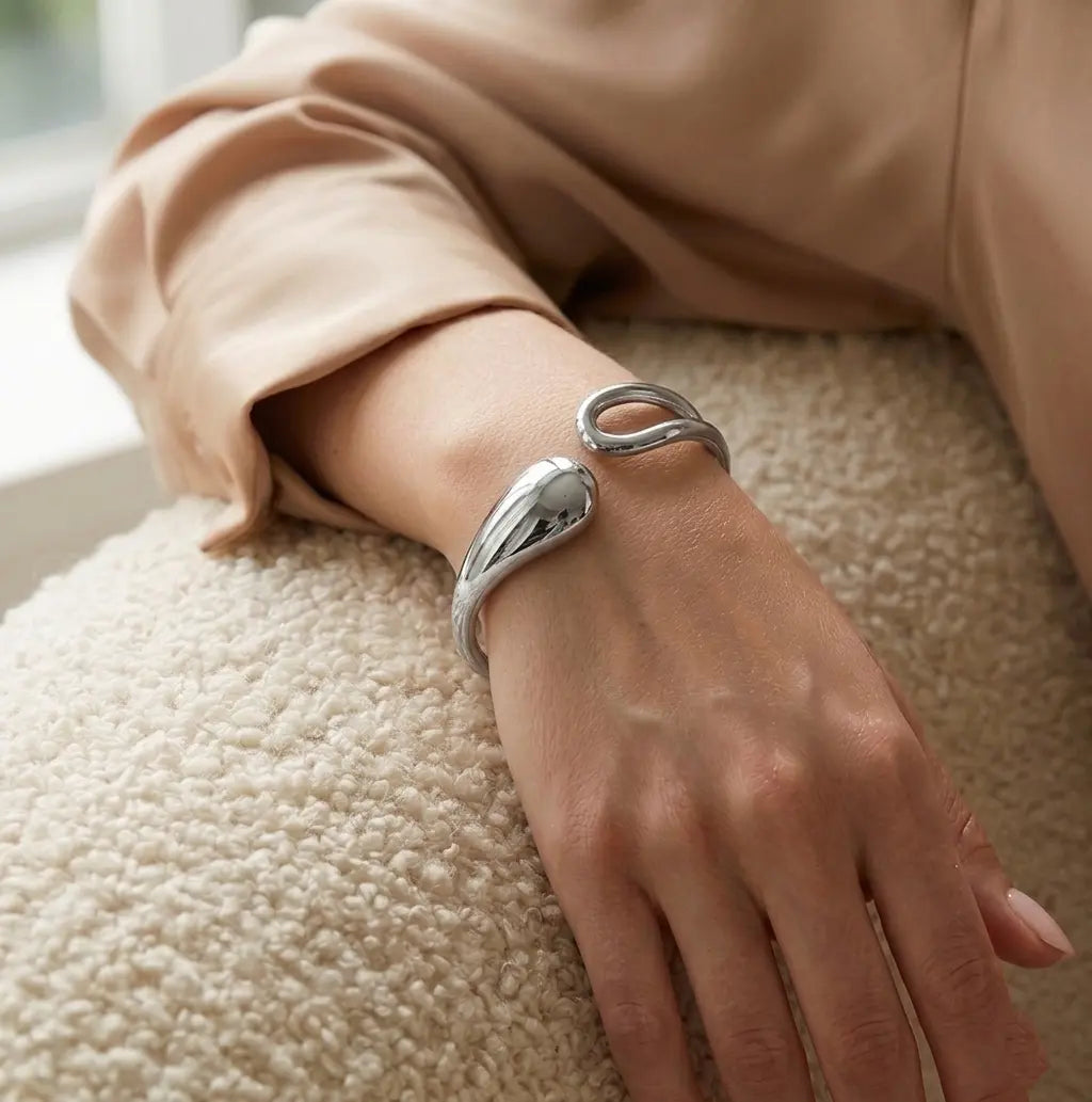 Bracelet doré Lyra - Aérienne porté au poignet, une pièce "statement" aux courbes élégantes et à la finition argentée brillante.