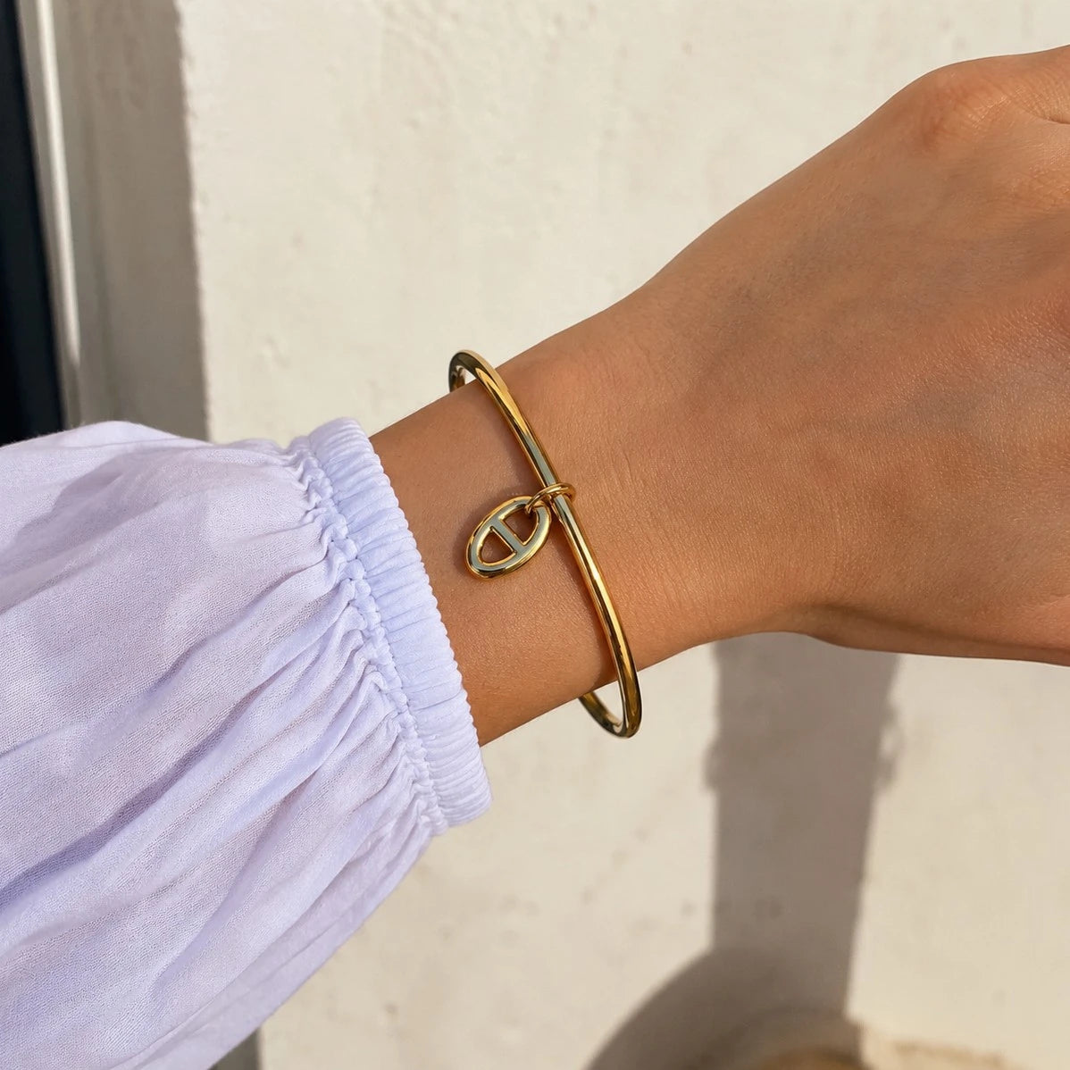 Poignet féminin portant le bracelet jonc Stella doré à maille marine, mis en valeur sur un fond clair.