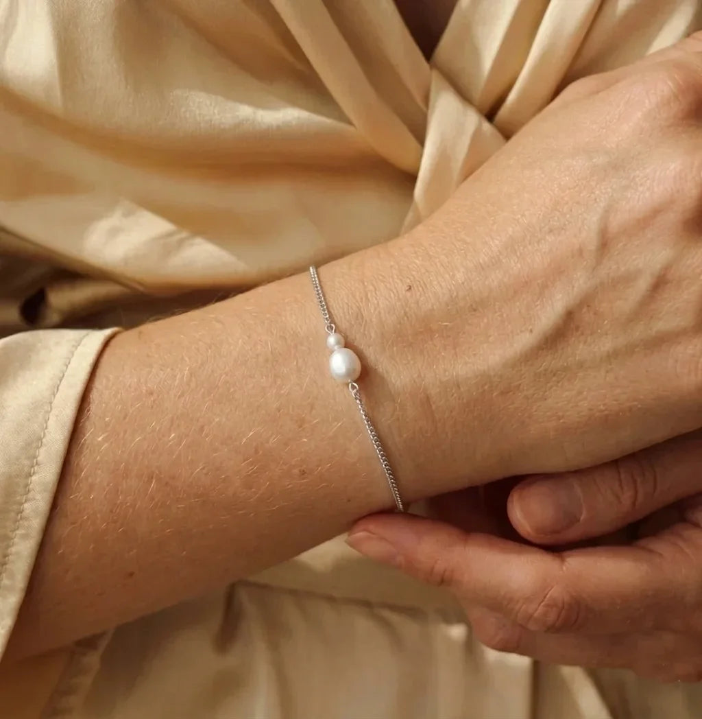 Bracelet gourmette Marine Sauvage argenté porté au poignet, mettant en avant la perle baroque naturelle et la maille acier.