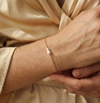 Bracelet gourmette Marine Sauvage doré porté au poignet, mettant en avant la perle baroque naturelle et la maille acier.