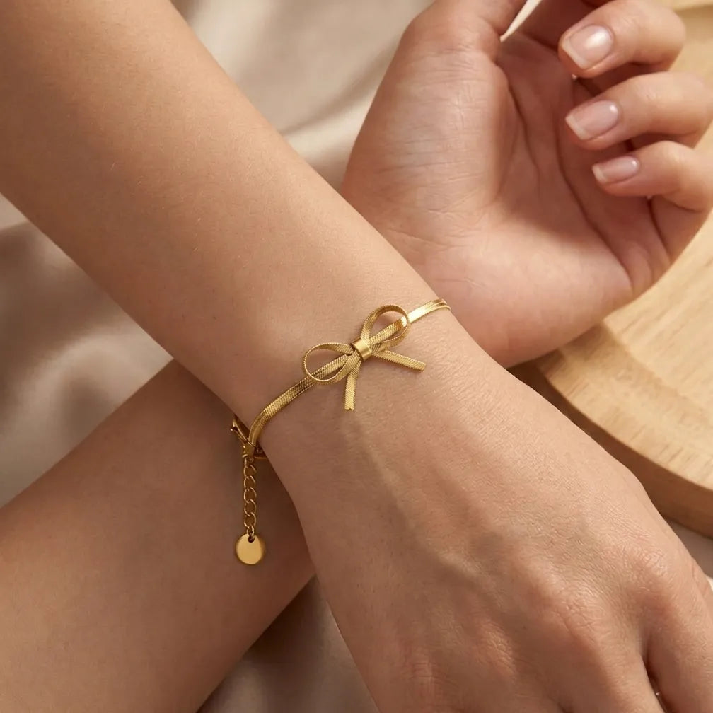 Craquez pour le bracelet Thalya - Noué en version dorée. Un bijou élégant en maille serpent orné d'un nœud délicat, idéal à porter au quotidien.