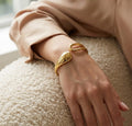Bracelet doré Lyra - Aérienne porté au poignet, une pièce "statement" aux courbes élégantes et à la finition dorée brillante.