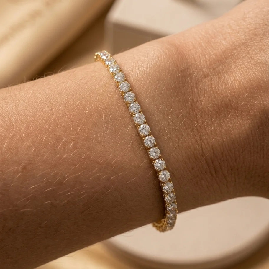 Gros plan du bracelet tennis Théa Absolue en finition dorée avec strass scintillants sur peau hâlée.