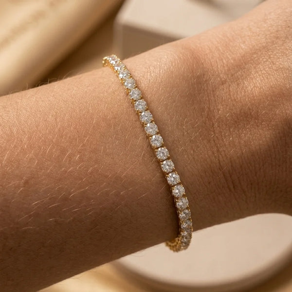 Gros plan du bracelet tennis Théa Absolue en finition dorée avec strass scintillants sur peau hâlée.