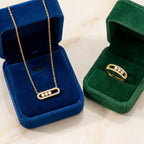 Collier doré dans un écrin de velours bleu et bague dorée dans un écrin vert, présentation de luxe pour la parure Sacha l'Instinctive.