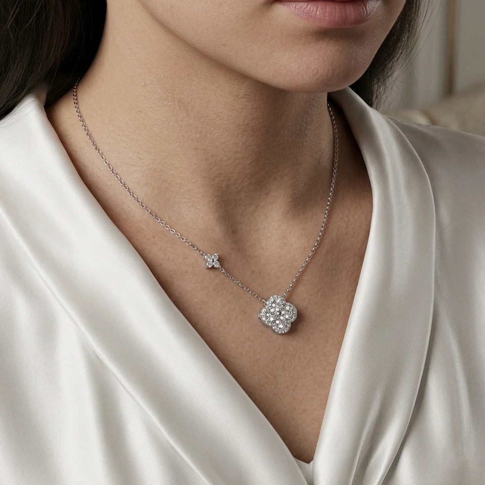 Collier Livia Radieuse argenté avec pendentif trèfle serti de cristaux porté par une mannequin sur une blouse en satin blanc.