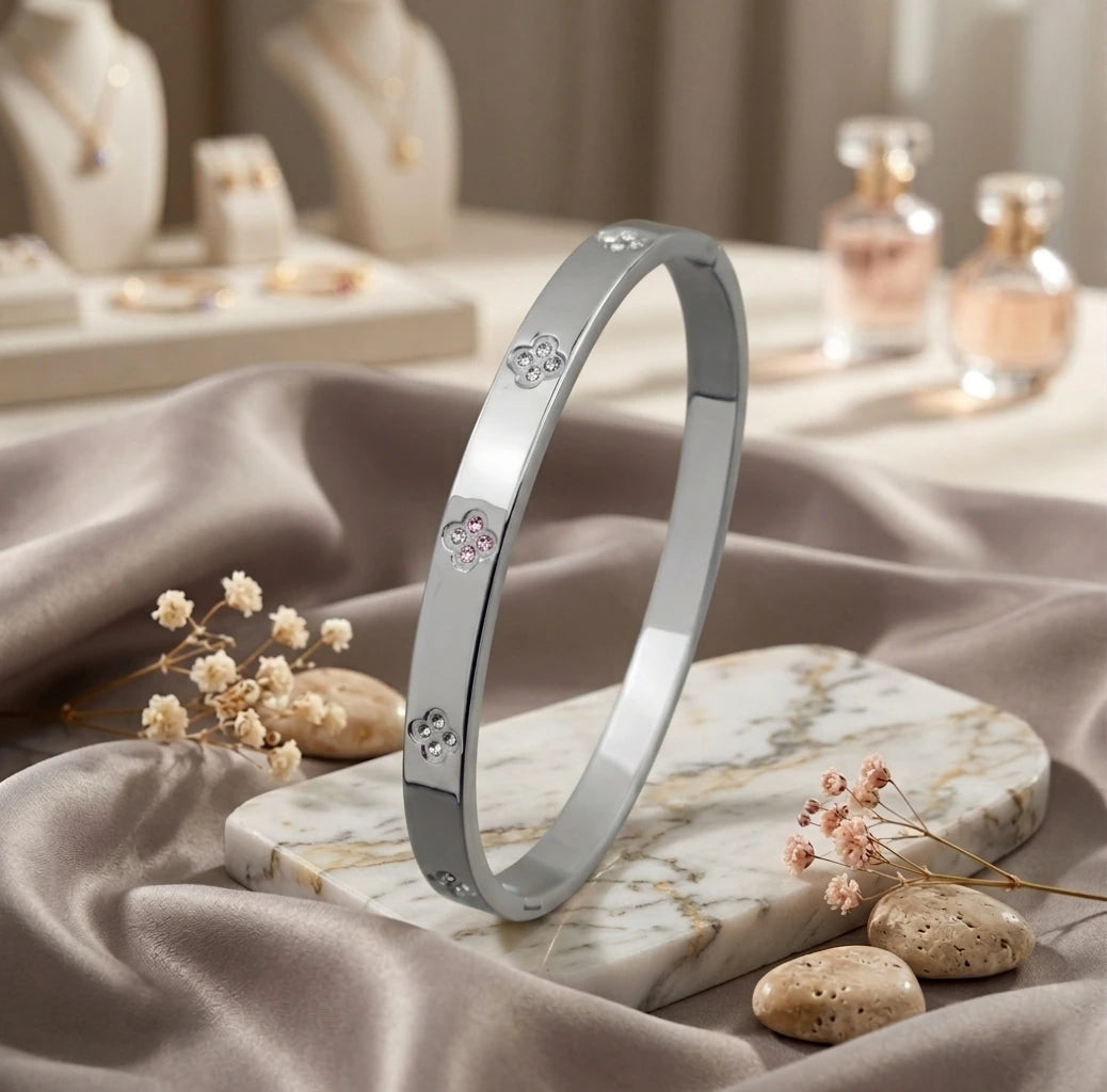 Bracelet jonc en argent poli Alix Distinguée présenté debout sur un socle en marbre blanc veiné de gris, entouré de fleurs séchées et galets