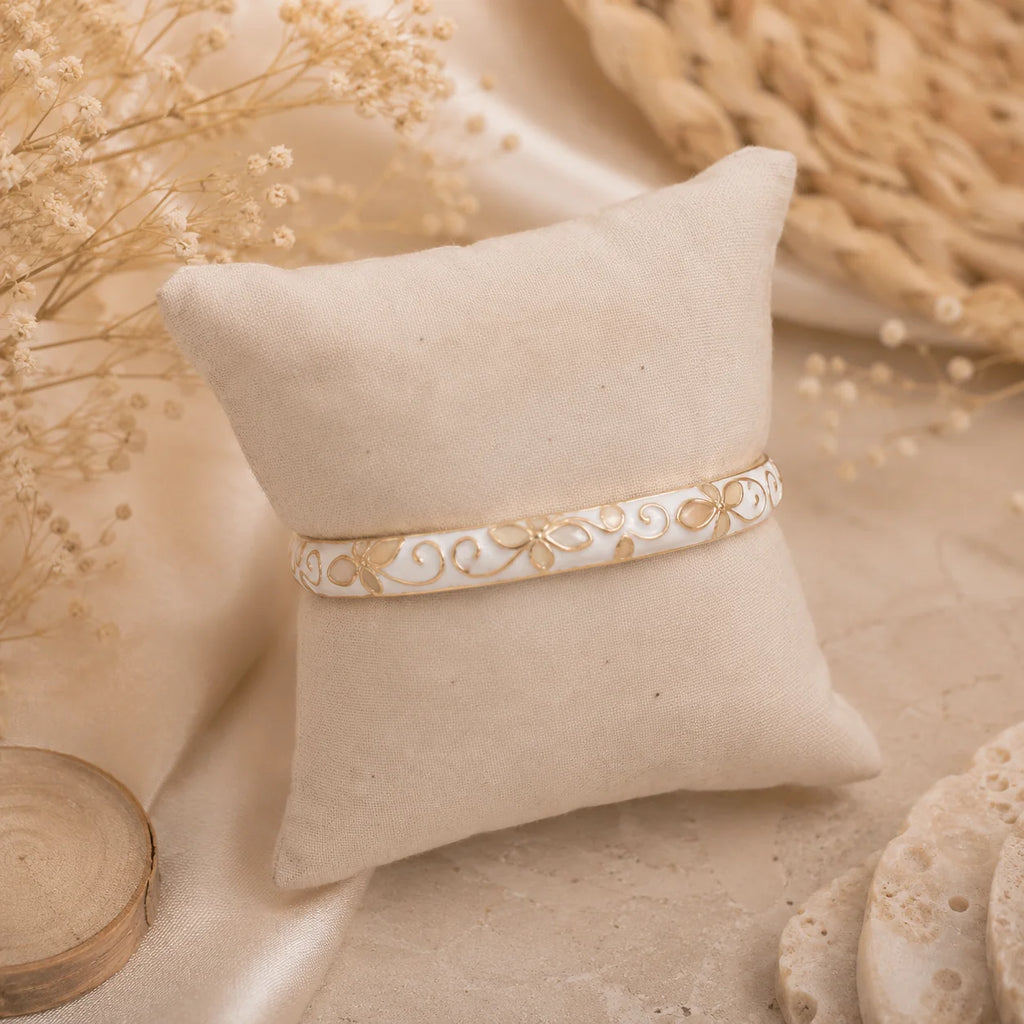 Bracelet jonc thaïlandais Sakura blanc nacré présenté sur un coussin en tissu écru.