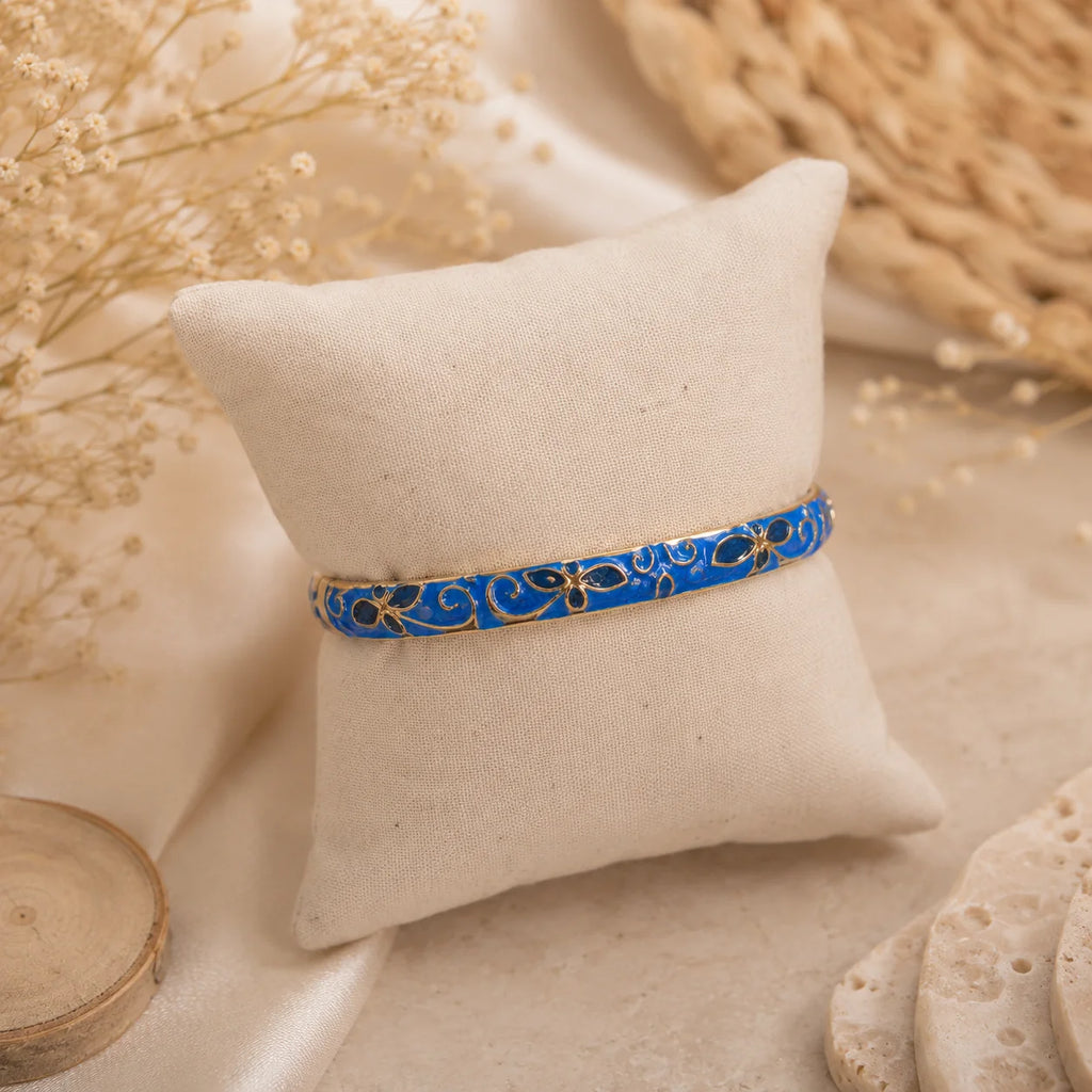 Bracelet jonc thaïlandais Sakura bleu royal présenté sur un coussin en tissu écru.