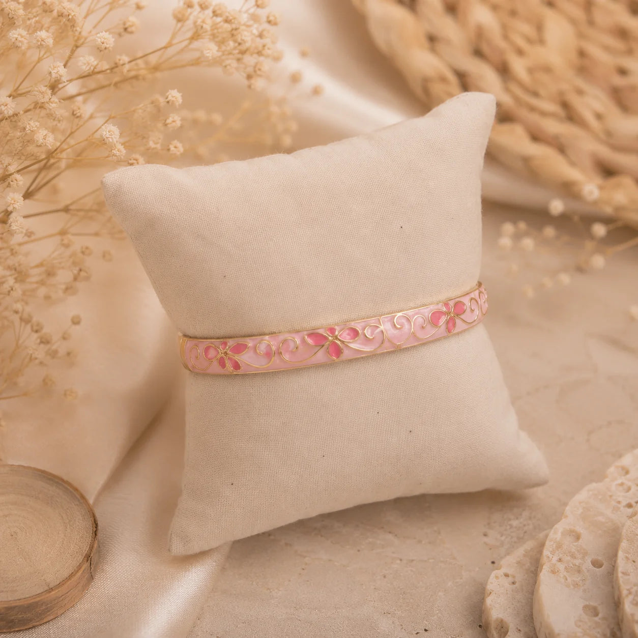 Bracelet jonc thaïlandais Sakura rose présenté sur un coussin en tissu écru.