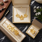 Vue de dessus de la parure dorée Colette - Épanouie présentée dans trois écrins de luxe ouverts. Les bijoux sont disposés sur un fond de marbre noir veiné, créant un contraste chic avec la texture satinée des fleurs argentées.